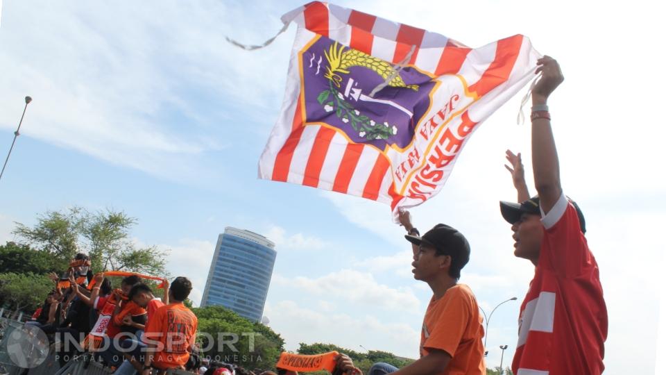 Dua orang pria tampak sedang membentangkan bendera kebesaran Persija.